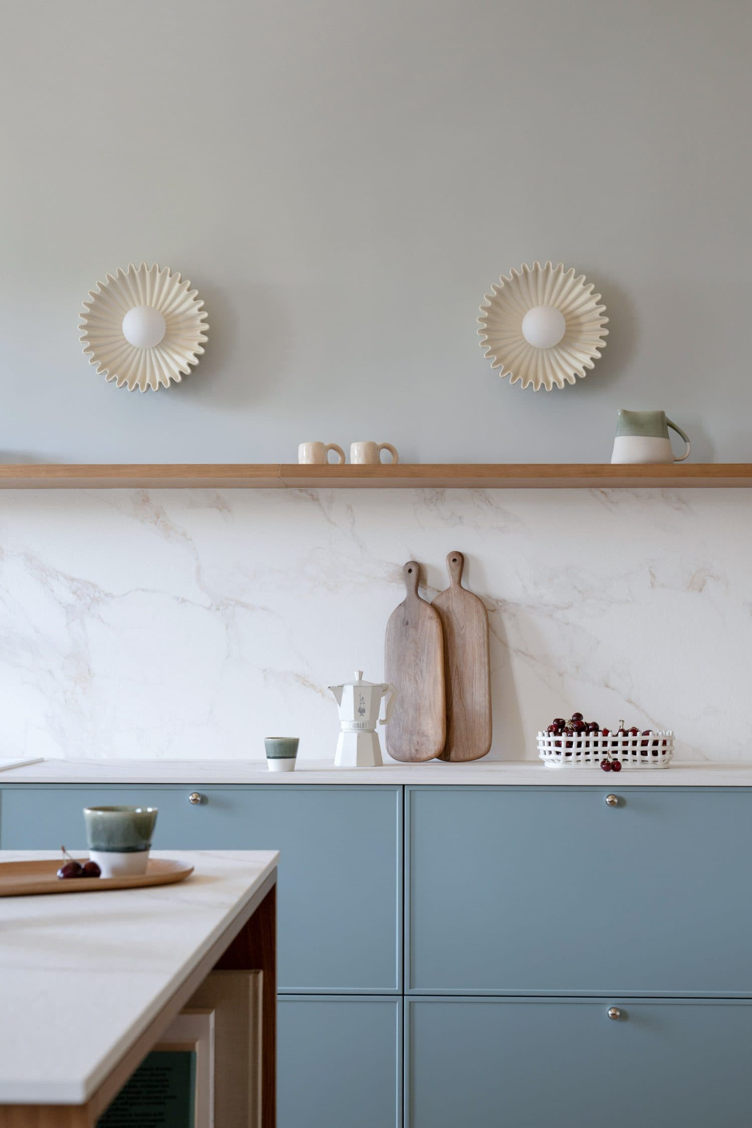 Cuisine bleu-gris, crédence marbre et appliques soleil